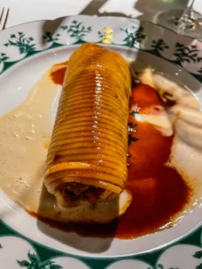 Photographie d'une timbale de pâtes artistiquement présentée au restaurant La Forêt Secrète par Jean Imbert à Disneyland Paris. Les ravioles, d'une forme cylindrique unique, sont nappées de sauces colorées, témoignant de la créativité du chef.