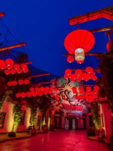 Photographie nocturne de l'allée illuminée de Kung Fu Panda Land of Awesomeness à Universal Studios Beijing, décorée de nombreuses lanternes chinoises rouges suspendues sous un ciel bleu foncé.