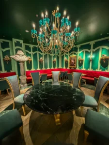 Intérieur thématisé du restaurant The Lair dans la zone Minion Land à Universal Studios Beijing, arborant un grand lustre en verre turquoise, des murs verts et des bustes de super-vilains.
