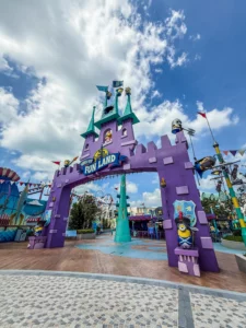 Photographie de l'arche d'entrée violette de Super Silly Fun Land (Minion Land) à Universal Studios Singapore, décorée avec des statues de Minions sous un grand ciel bleu.