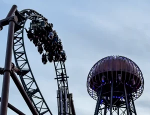 Un train du coaster Voltron Nevera amorçant une inversion au-dessus des bâtiments thématiques, juste à côté de sa haute tour métallique de style bobine Tesla à Europa-Park.